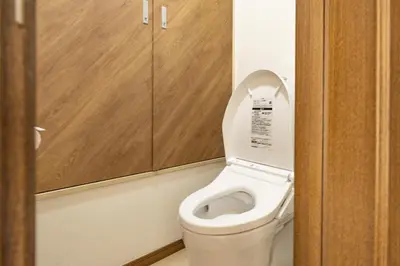 a small bathroom with a toilet with wooden cabinets at Near Shinjuku 2-Story Family & Group-Friendly Home 5 Bedrooms, Fits 14 Guests in Tokyo