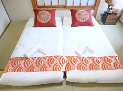 two beds with red pillows in a bedroom at Two bathrooms, two toilets 6 mins walking distance from Keisei Takasago Station in Tokyo