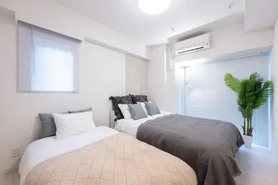 a bedroom with two beds and a potted plant at LIVCITY Kinshicho 802 in Tokyo