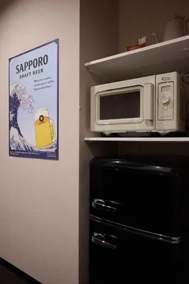 a microwave sitting on a shelf next to a refrigerator at Blossom House Shibuya in Tokyo