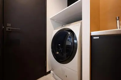 a washer and dryer in a bathroom next to a door at Blossom House Shibuya in Tokyo