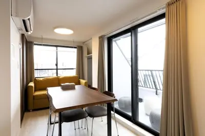 a living room with a table and chairs and a large window at SLEEPLAB THE STAY Casual \u6c60\u888b -Ikebukuro- in Tokyo