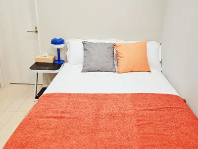 a bedroom with a bed with an orange blanket on it at \u677f\u6a4b\u99c5\u5f92\u6b692\u5206 \u6c60\u888b\u307e\u3067\u96fb\u8eca2\u5206 \u5b8c\u5168\u8cb8\u5207 \u6700\u59274\u4eba in Tokyo