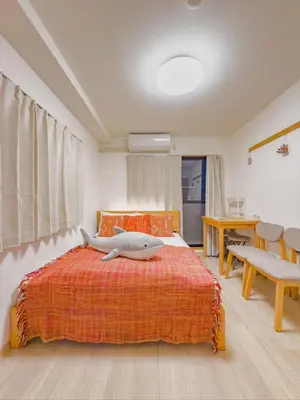 a bedroom with a bed with an orange blanket and a table at \u62bc\u4e0a hotel \u5927\u5e8a\u623f -SM0387 in Tokyo