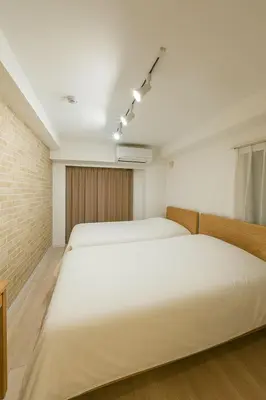 a bedroom with two white beds and a brick wall at \u9526\u7cfb\u753a hotel -SM0380 in Tokyo