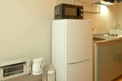 a microwave sitting on top of a refrigerator in a kitchen at \u30e1\u30be\u30f3\u67cf\u6728 in Tokyo