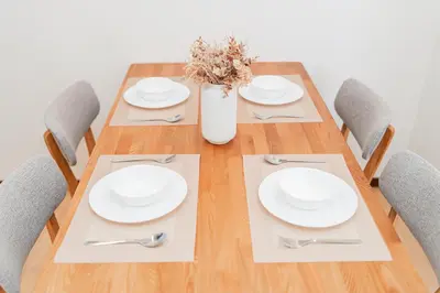 a wooden table with chairs and plates and a vase with flowers at GLOU Shibuya House - A Private House in Tokyo Shinjuku & Shibuya Area in Tokyo