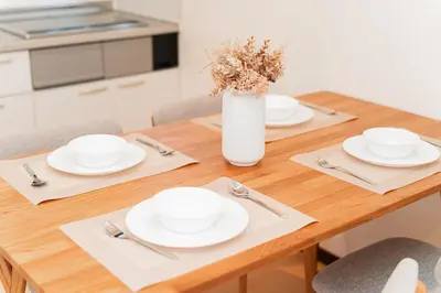 a wooden table with white dishes and a vase with flowers at GLOU Shibuya House - A Private House in Tokyo Shinjuku & Shibuya Area in Tokyo