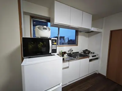 a kitchen with a microwave on top of a refrigerator at ZYZ Negishi\u9daf\u8c37\u99c5 TT0257 in Tokyo