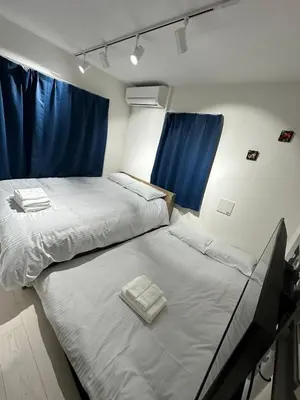 two beds in a room with blue curtains at \u65b0\u7bc9OPEN GREW OJI residence201 in Tokyo