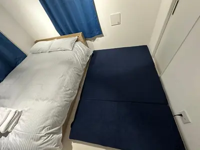 a small bedroom with a bed and a blue curtain at \u65b0\u7bc9OPEN GREW OJI residence201 in Tokyo