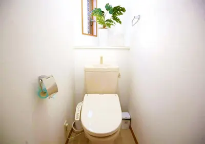 a bathroom with a toilet with a plant on the wall at \u6771\u4eac\u90fd\u845b\u98fe\u533a\u306e\u8cb8\u5207\u4e00\u8ed2\u5bb6 in Tokyo
