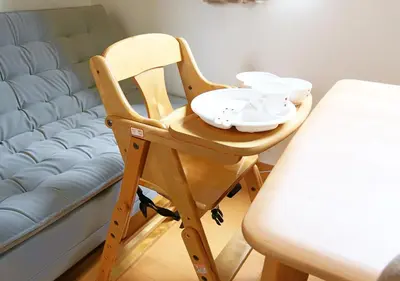 a wooden high chair with dishes on it next to a bed at \u6771\u4eac\u90fd\u845b\u98fe\u533a\u306e\u8cb8\u5207\u4e00\u8ed2\u5bb6 in Tokyo