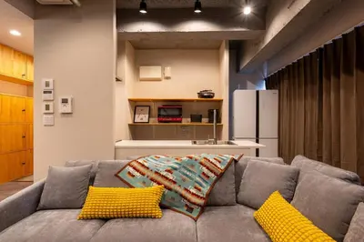 a living room with a gray couch with yellow pillows at Good Space Hotel Oshiage in Tokyo