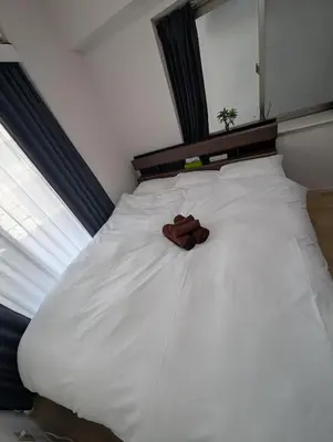 a white bed with a pair of brown shoes on it at MerisuKabukicho,Tokyo in Tokyo