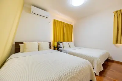 two beds in a room with yellow curtains at Shinjuku Newly renovated 4LDK House! in Tokyo