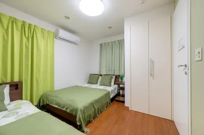 two beds in a room with green curtains at Shinjuku Newly renovated 4LDK House! in Tokyo
