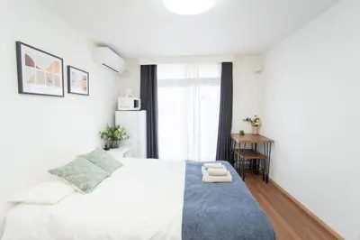 a bedroom with a white bed with a blue rug at \u590f\u7f8e\u30db\u30c6\u30eb 303\u9ad8\u7ea7\u72ec\u680b\u522b\u5885 \u72ec\u7acb\u536b\u6d74 \u5730\u94c1\u7ad9\u6b65\u884c\u4e94\u5206\u949f\u6210\u7530\u673a\u573a-\u7fbd\u7530\u673a\u573a-\u4e0a\u91ce-\u6674\u7a7a\u5854\u4e00\u7ebf\u76f4\u901a in Tokyo