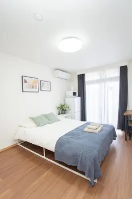 a bedroom with a large bed with a blue blanket at \u590f\u7f8e\u30db\u30c6\u30eb 303\u9ad8\u7ea7\u72ec\u680b\u522b\u5885 \u72ec\u7acb\u536b\u6d74 \u5730\u94c1\u7ad9\u6b65\u884c\u4e94\u5206\u949f\u6210\u7530\u673a\u573a-\u7fbd\u7530\u673a\u573a-\u4e0a\u91ce-\u6674\u7a7a\u5854\u4e00\u7ebf\u76f4\u901a in Tokyo