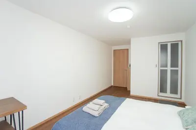 a white bedroom with a bed and a table at \u590f\u7f8e\u30db\u30c6\u30eb 303\u9ad8\u7ea7\u72ec\u680b\u522b\u5885 \u72ec\u7acb\u536b\u6d74 \u5730\u94c1\u7ad9\u6b65\u884c\u4e94\u5206\u949f\u6210\u7530\u673a\u573a-\u7fbd\u7530\u673a\u573a-\u4e0a\u91ce-\u6674\u7a7a\u5854\u4e00\u7ebf\u76f4\u901a in Tokyo