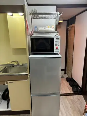 a microwave on top of a refrigerator in a kitchen at Miaoyi Shinokubo in Tokyo