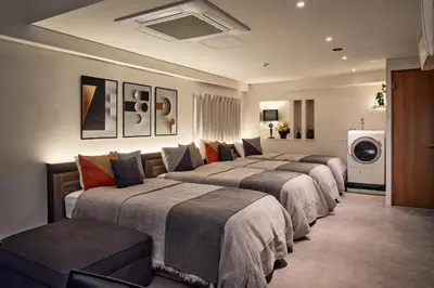 a hotel room with three beds and a washing machine at shibuya donkey stay in Tokyo