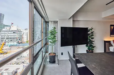 a room with a balcony with a tv and a large window at shibuya donkey stay in Tokyo