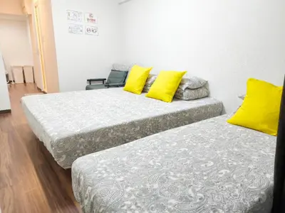 two beds with yellow pillows in a room at Z HOME - Self Check in in Tokyo