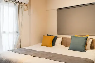 a bedroom with a bed with yellow and blue pillows at \u30db\u30c6\u30eb\u5bcc\u58eb\u898b\u30de\u30f3\u30b7\u30e7\u30f3 in Tokyo