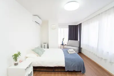 a white bedroom with a bed and a chair at Natumi \u30db\u30c6\u30eb 304 \u9ad8\u7ea7\u72ec\u680b\u522b\u5885 \u8f66\u7ad9\u6b65\u884c\u4e94\u5206\u949f \u6210\u7530-\u7fbd\u7530-\u4e0a\u91ce\u4e00\u7ebf\u76f4\u8fbe in Tokyo