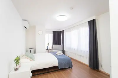 a white bedroom with a bed and a window at Natumi \u30db\u30c6\u30eb 304 \u9ad8\u7ea7\u72ec\u680b\u522b\u5885 \u8f66\u7ad9\u6b65\u884c\u4e94\u5206\u949f \u6210\u7530-\u7fbd\u7530-\u4e0a\u91ce\u4e00\u7ebf\u76f4\u8fbe in Tokyo