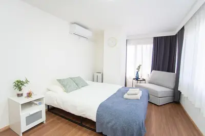 a white bedroom with a bed and a chair at Natumi \u30db\u30c6\u30eb 304 \u9ad8\u7ea7\u72ec\u680b\u522b\u5885 \u8f66\u7ad9\u6b65\u884c\u4e94\u5206\u949f \u6210\u7530-\u7fbd\u7530-\u4e0a\u91ce\u4e00\u7ebf\u76f4\u8fbe in Tokyo