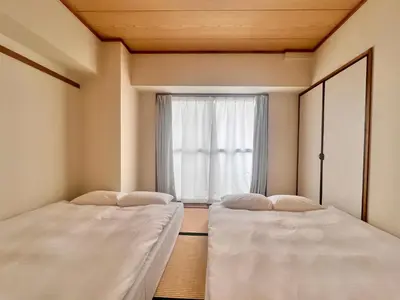 two beds in a room with a window at LoveAsakusa Stay 6 Iriya Station Ueno Station 2\u30fc6\u4eba \u30a8\u30ec\u30d9\u30fc\u30bf\u30fc WIFI \u6d45\u8349 \u65b0\u5bbf \u6e0b\u8c37 \u9280\u5ea7 \u7bc9\u5730 \u6d45\u8349 \u539f\u5bbf\u8fd1\u3044 in Tokyo