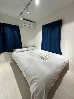 a bedroom with a large white bed with blue curtains at \u65b0\u7bc9OPEN GREW OJI residence202 in Tokyo