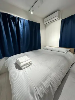 a bedroom with a large white bed with blue curtains at \u65b0\u7bc9OPEN GREW OJI residence301 in Tokyo