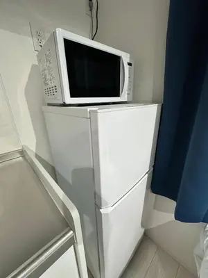 a microwave oven sitting on top of a refrigerator at \u65b0\u7bc9OPEN GREW OJI residence301 in Tokyo