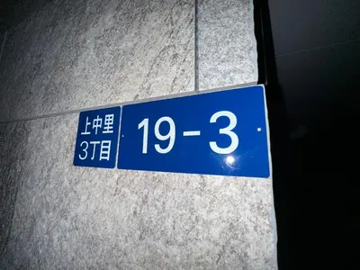 a blue street sign on the side of a sidewalk at \u65b0\u7bc9OPEN GREW OJI residence302 in Tokyo