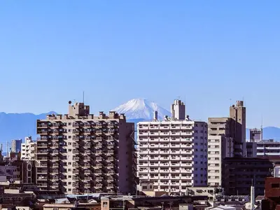 a group of tall buildings with a mountain in the background at Triphome Nakano 1 bedroom in Tokyo