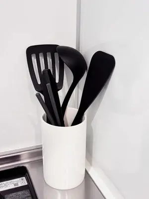 a white cup filled with black utensils on a counter at Triphome Nakano 1 bedroom in Tokyo