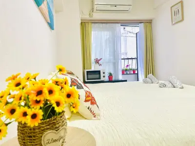a bedroom with a vase of sunflowers on a bed at G25-\u65b0\u5bbf\u6700\u4e2d\u5fc3 \u6771\u65b0\u5bbf\u99c53\u5206-Shinjuku center 4 mins to ST Max 3P \u76f4\u8fbe\u65b0\u5bbf \u6e0b\u8c37 \u8868\u53c2\u9053 \u6c60\u888b \u4e0a\u91ce \u4ee3\u4ee3\u6728 \u9280\u5ea7 \u539f\u5bbf in Tokyo