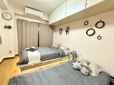 a bedroom with two beds and a clock on the wall at Ikebukuro Sugamo B01 in Tokyo