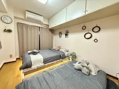 a bedroom with two beds and a clock on the wall at Ikebukuro Sugamo B01 in Tokyo