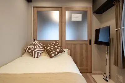 a bedroom with a bed with a television and a door at Shinjuku\u65b0\u5bbf\u5546\u5708-\u6771\u65b0\u5bbf-2Room-Max5P-\u548c\u5f0f\u98ce\u683c-\u4e0a\u91ce\u65b0\u5bbf\u6c60\u888b\u6e0b\u8c37\u76f4\u8fbe in Tokyo