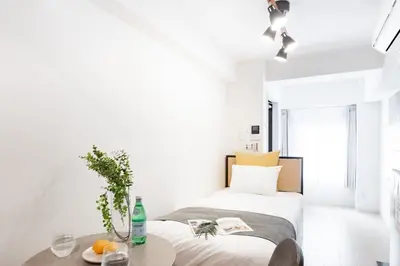 a white bedroom with two beds and a table at GLiCION\u738b\u5b50 in Tokyo