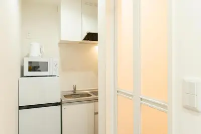 a small kitchen with a refrigerator and a microwave at T4U Shinjyuku Okubo in Tokyo