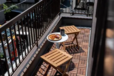 a table and two chairs on a balcony with a plate of food at T4U Shinjyuku Okubo in Tokyo
