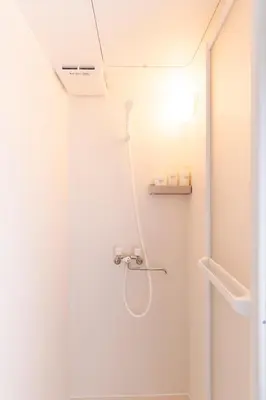 a white bathroom with a shower and a toilet at T4U Shinjyuku Okubo in Tokyo