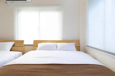 two beds in a bedroom with white walls and windows at Ueno-an 4,5F in Tokyo