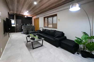 a living room with a black couch and a table at Rakuna Inn \u5bdb sasazuka3 in Tokyo