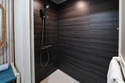 a shower stall in a bathroom with wooden walls at Rakuna Inn \u5bdb sasazuka3 in Tokyo